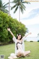 A woman sitting on the grass with her arms outstretched.