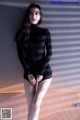 A woman in a black turtle neck sweater and shorts posing for a picture.