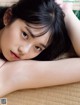 A young woman laying on top of a bamboo mat.