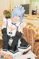 A woman in a maid outfit sitting on a couch.