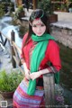 A woman in a red shirt and green scarf posing for a picture.