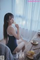 A woman sitting at a table eating a lemon.