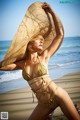 A woman in a bikini and hat on the beach.