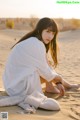 A woman sitting on top of a sandy beach.