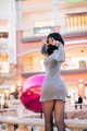 A woman in a gray dress and black tights posing for a picture.