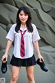 A woman in a school uniform holding a pair of shoes.