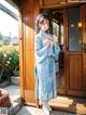 A woman in a blue dress standing in front of a wooden door.