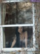 A woman looking out of a window in an abandoned building.