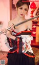 A woman in a kimono holding a samurai sword.