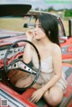 A woman sitting in the driver's seat of a red car.