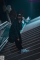 A woman wearing a cat ears mask standing on a set of stairs.