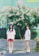 Two young women standing next to each other in front of a tree.