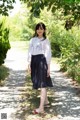 A woman standing on a path in a park.