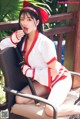 A woman in a red and white outfit sitting on a chair.