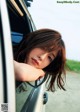 A young woman leaning out the window of a car.