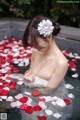 A woman in a bathtub filled with rose petals.